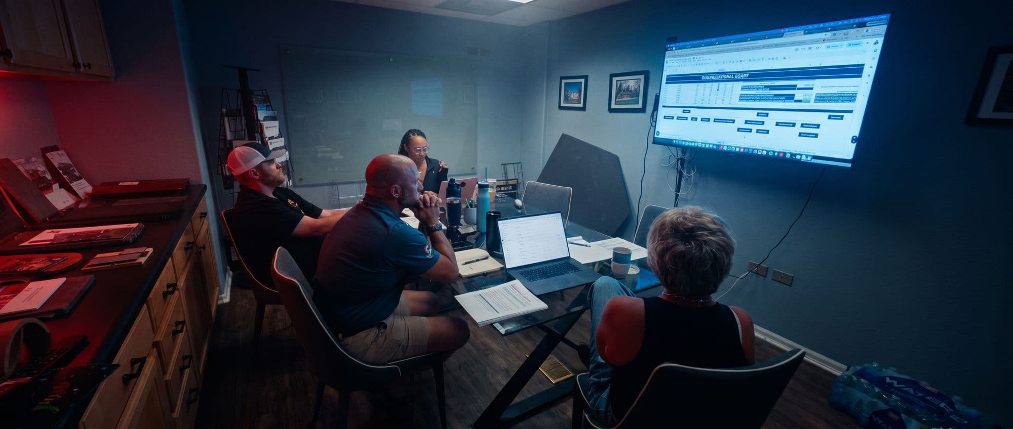 A member team works through a dashboard on the wall screen with a Roofing Academy coach.