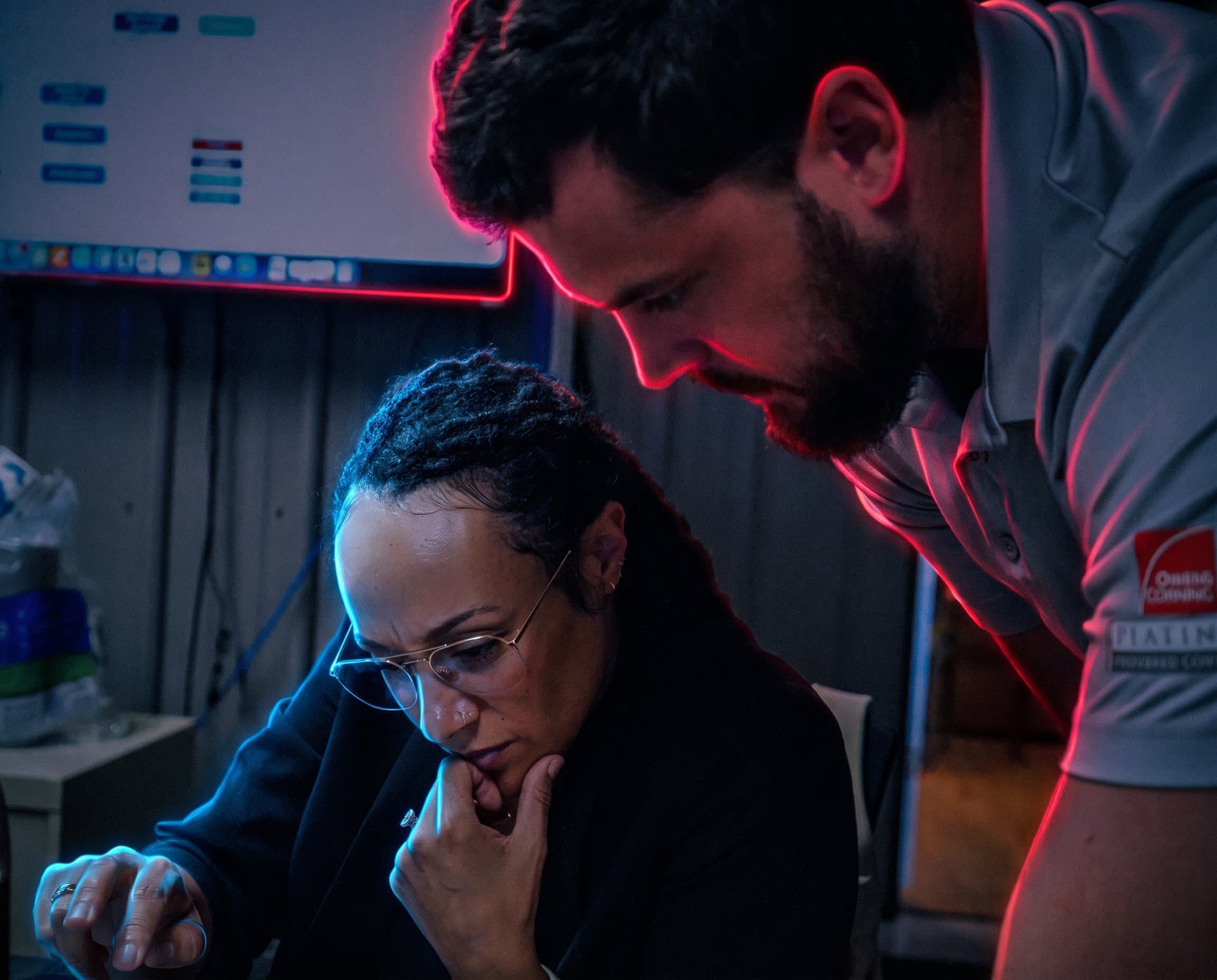 A Roofing Academy coach and a roofing company owner work through a problem together at his laptop.