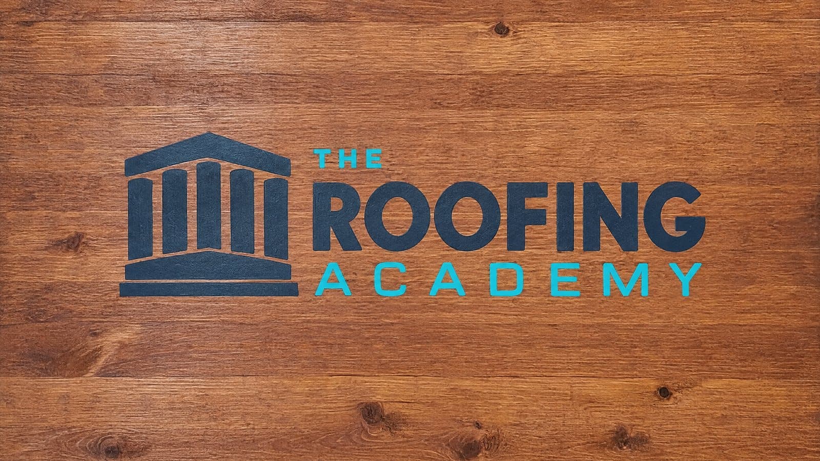The Roofing Academy logo on a stained wood sign.