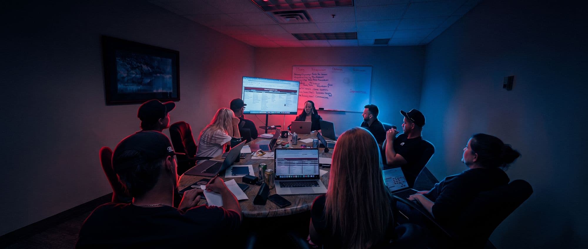 A Roofing Academy coaching session with a member team around the conference table, the agenda on the wall screen.